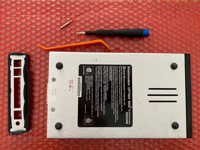 Picture of the bottom of a Hayes Optima 9600 modem and some tools